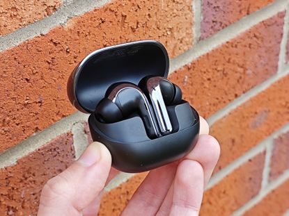 The Xiaomi Buds 4 Pro against a brick wall background