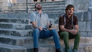 Nicolas Cage laughing and sitting next to Pedro Pascal in The Unbearable Weight of Massive Talent