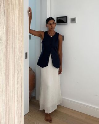 British fashion influencer posing in a long vest and white maxi skirt