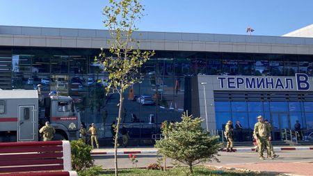 Law enforcement officers patrol an area outside the airport in Makhachkala, Russia