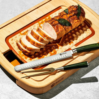 A HexClad carving / cutting Board with a pork tenderloin sliced with the free carvery knife set that's included 