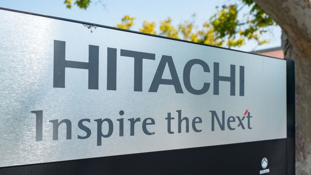 The word HITACHI on a sign, with the slogan &amp;#039;INSPIRE THE NEXT&amp;#039; beneath it