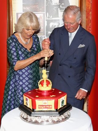 Britain's Prince Charles, Prince of Wales (R) and his wife Britain's Camilla, Duchess of Cornwall, react as they cut into a celeratory cake during a reception to mark the 500th Anniversary of the Royal Mail, at Merchant Taylor's Hall in London on September 6, 2016. / AFP / POOL / Chris Jackson