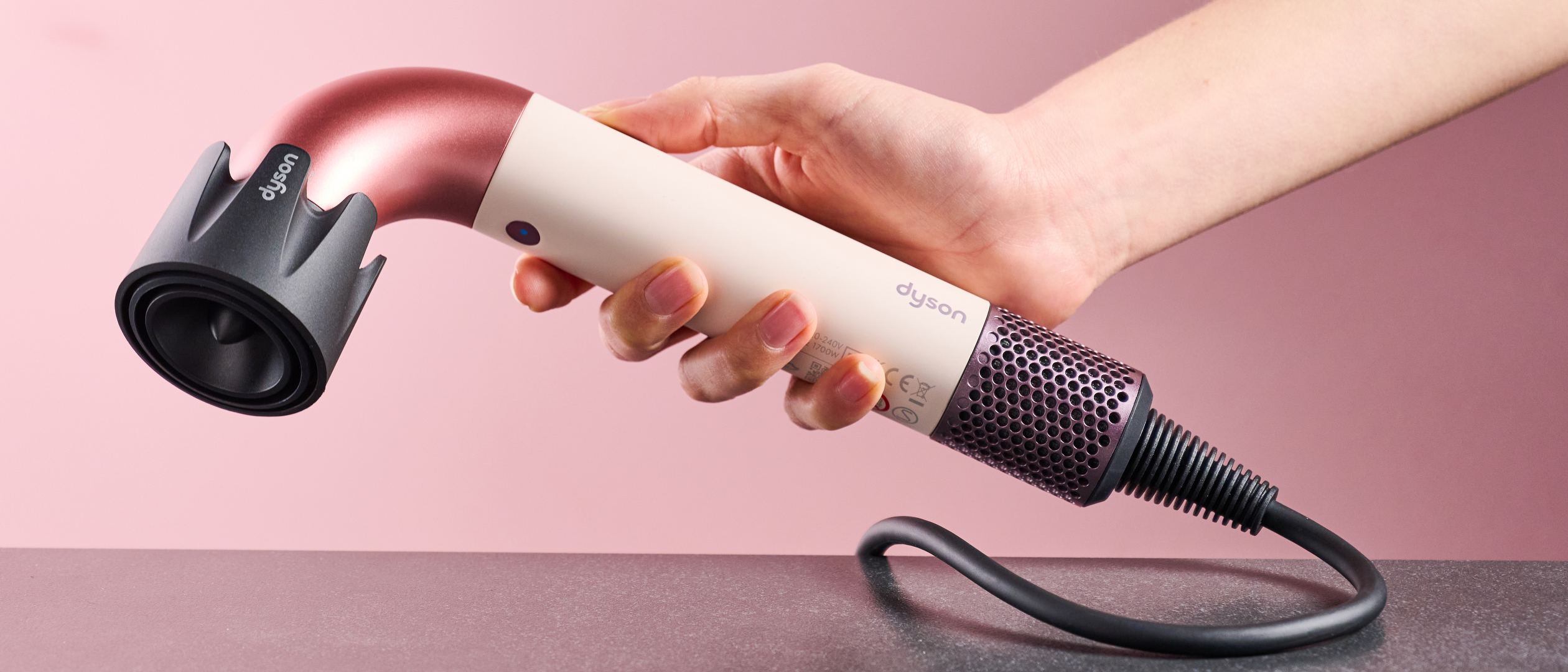 Dyson Supersonic r hair dryer in reviewer&#039;s hand, with Powerful air attachment
