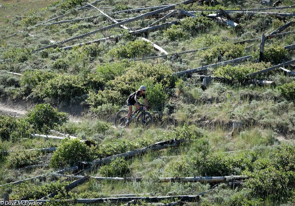 Amy Beisel (Pro Cycling) descending through fallen trees with a small gap over Rose Grant