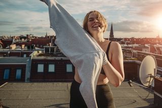 Preventing injury: portrait of smiling woman wearing t-shirt on rooftop against dramatic sky