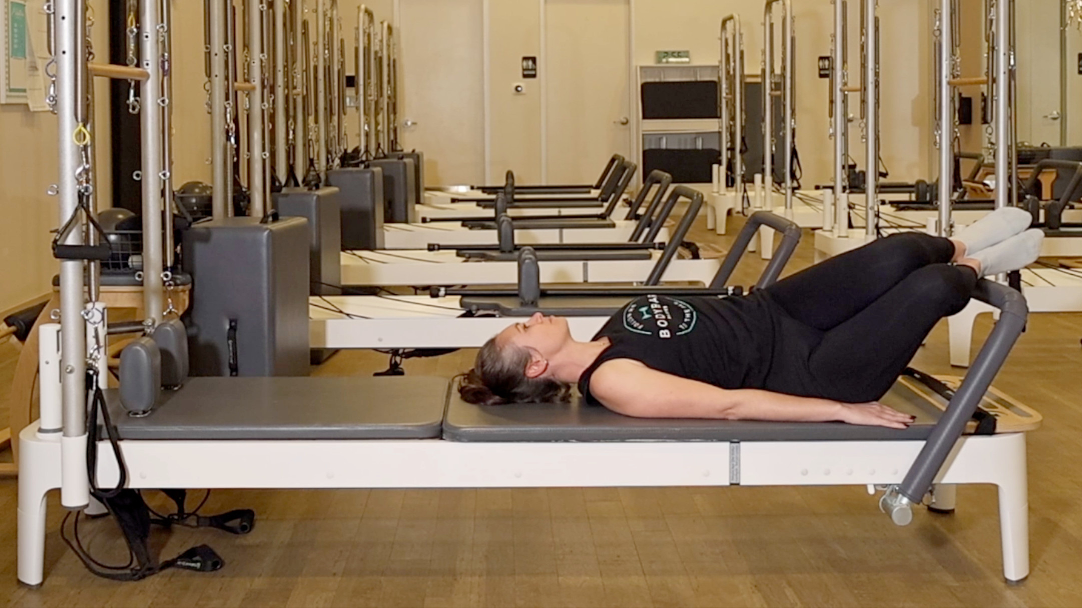 Woman demonstrating a Pilates exercise on the carriage of a Pilates reformer machine
