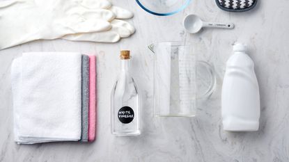 Flat lay of white vinegar, spray bottle, cloths and rubber gloves