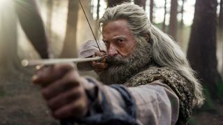 Hugh Jackman as Robin Hood shooting a bow and arrow.