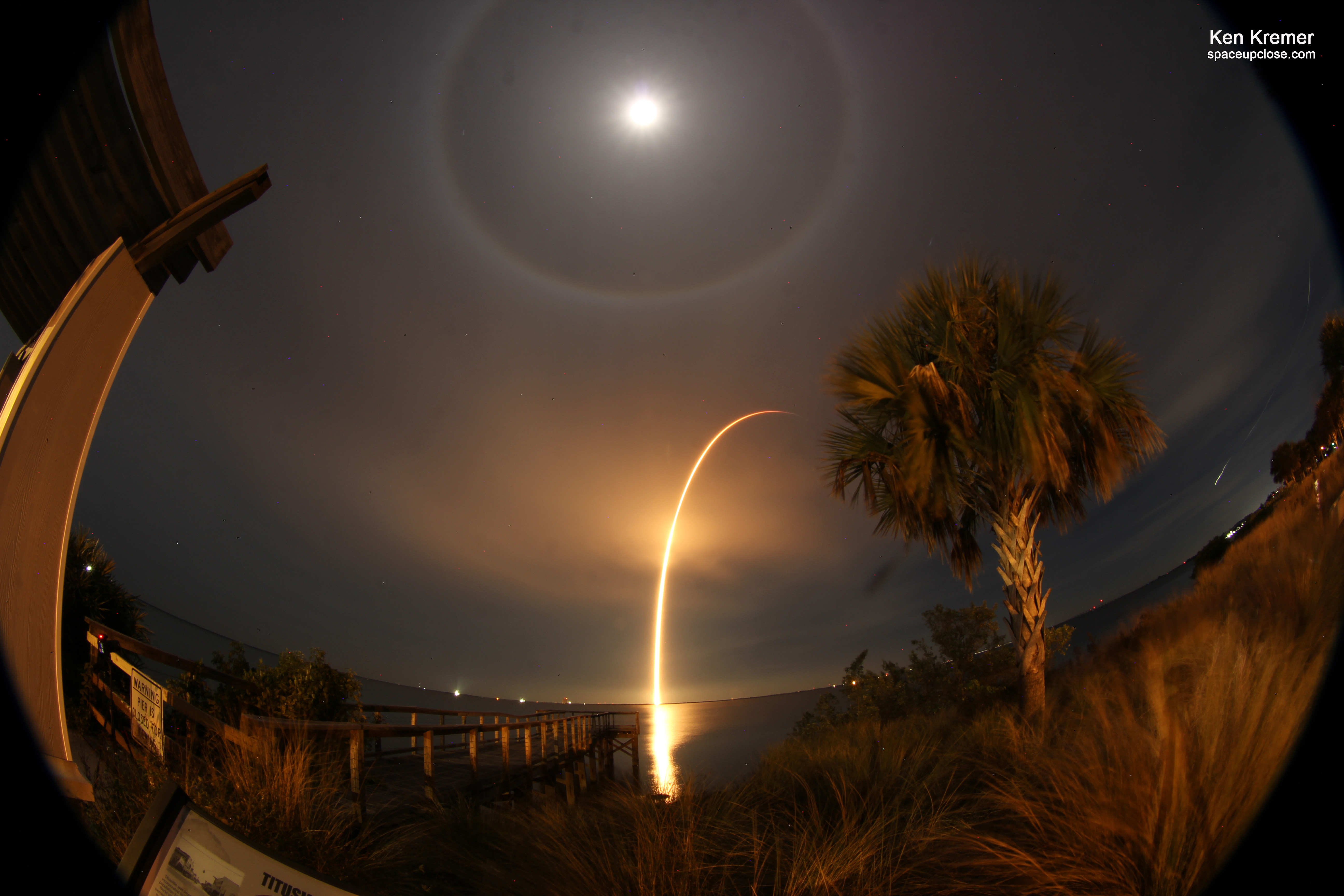 La luna llena se puede ver en el cielo sobre un arco formado por el lanzamiento de un cohete.