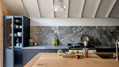 Kitchen with dark gray cabinets and marble backsplash with wooden island