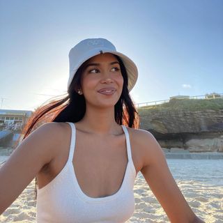 Woman wearing a white bucket hat on the beach.