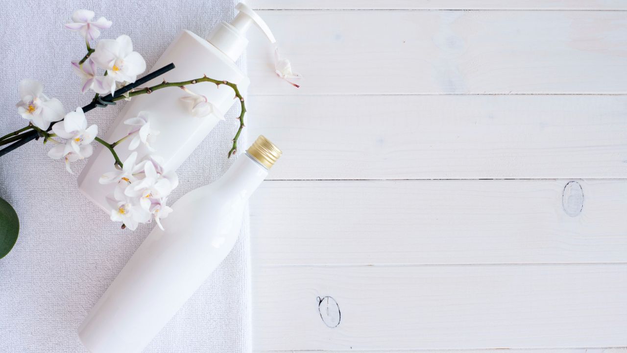 Soothing skincare bottles and orchid on white backdrop