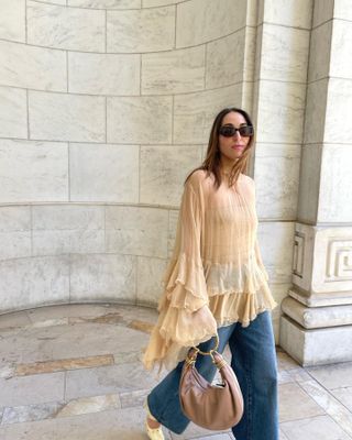 Anna wears a ruffle top, jeans, white flats, and a chloe bag.