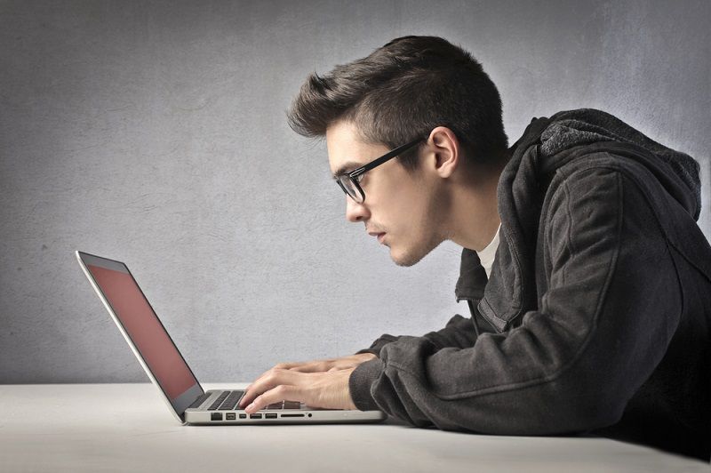 A young man looking at a laptop computer.