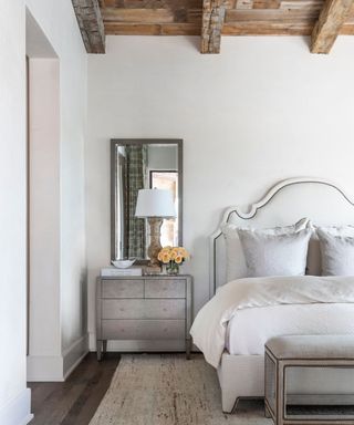 rustic french country bedroom with wood ceiling beams and a gray color scheme below