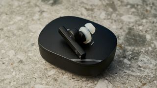 a photograph of one black earbud by final with a long, angular stem and black casing, silicone ear tips, resting upon a black oval case reading 'final' with three decorative hexagons