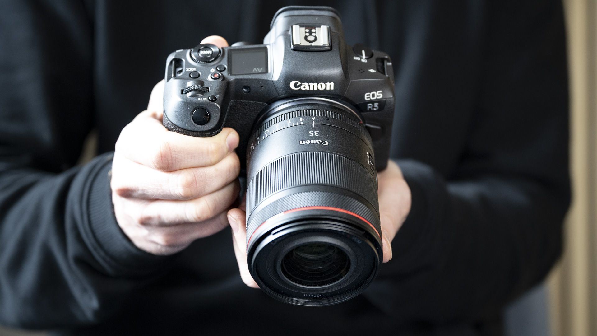 The Canon RF 35mm F1.4 lens attached to a Canon EOS R5, in the hand