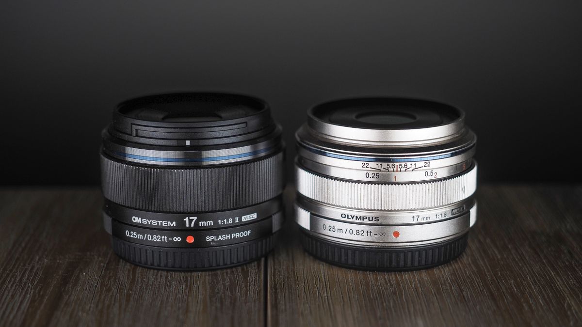 OM System M.Zuiko 17mm f/1.8 II next to an Olympus M.Zuiko 17mm lens on a wooden surface