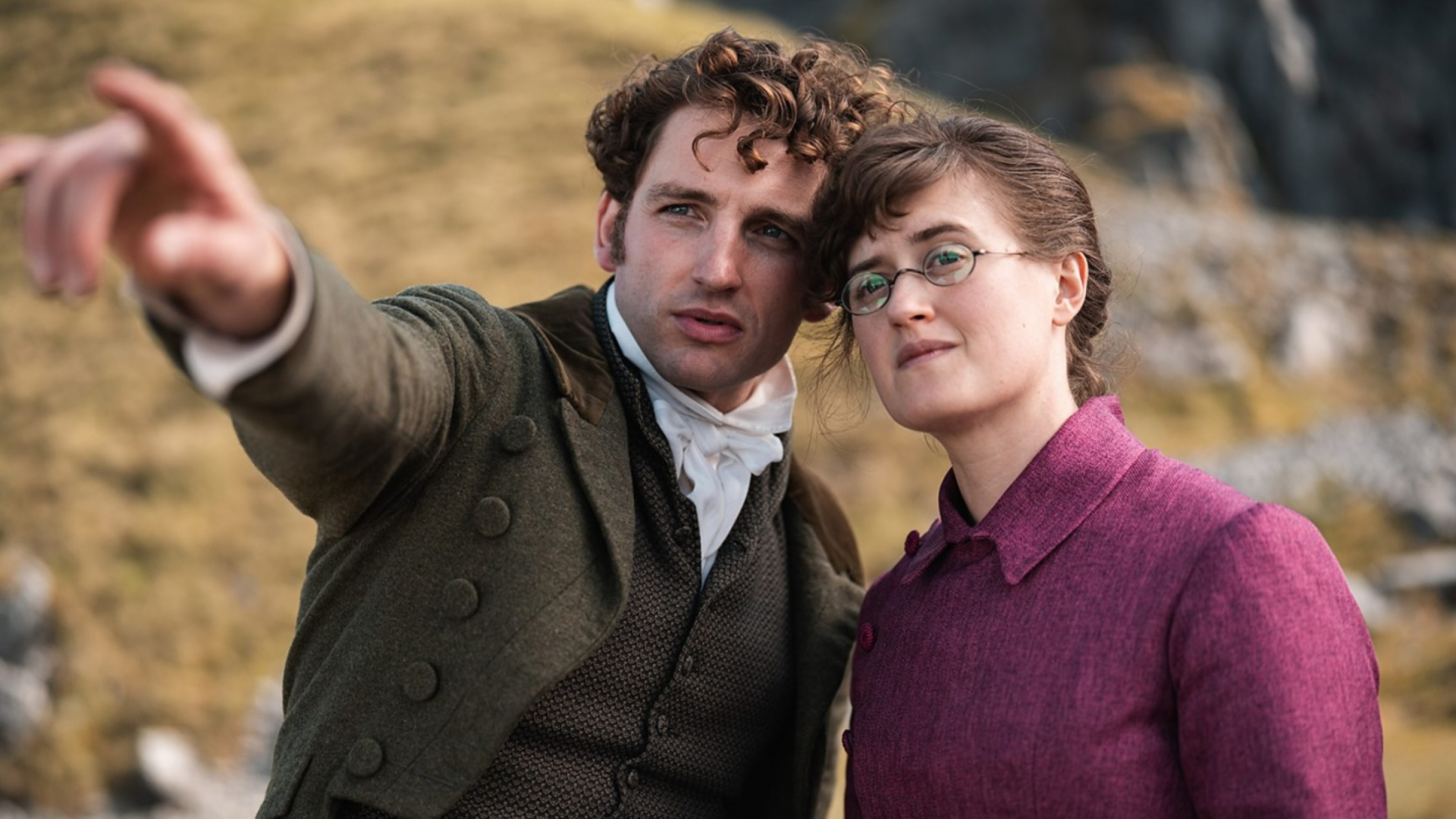 A man and woman (Laurie Davidson as Mr Ryder and Ella Bruccoleri as Mary Bennet) in Regency Era clothing stand outdoors, as the man points into the distance, in 'The Other Bennet Sister.'
