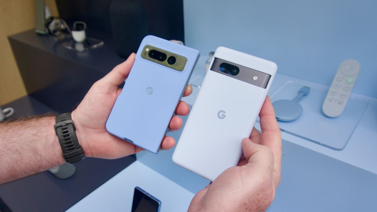 The Google Pixel Fold and Pixel 7a held in two hands. The Pixel Fold is noticeably shorter and wider in folded mode.
