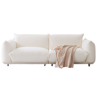 A white boucle sofa with throw cushions and a neutral blanket
