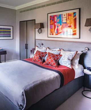 Grey room, bed with contrasting cushions, padded headboard, abstract art