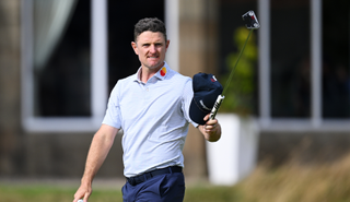 Justin Rose raises his putter up in the air after holing a birdie putt