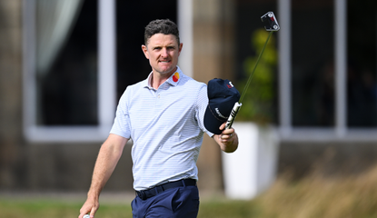 Justin Rose raises his putter up in the air after holing a birdie putt