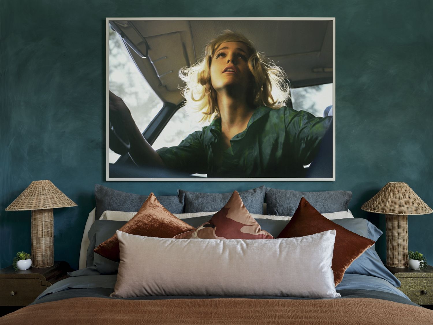 A bedroom with teal, lime wash walls with colorful soft furnishings on a styled bed and rattan woven bedside lamps