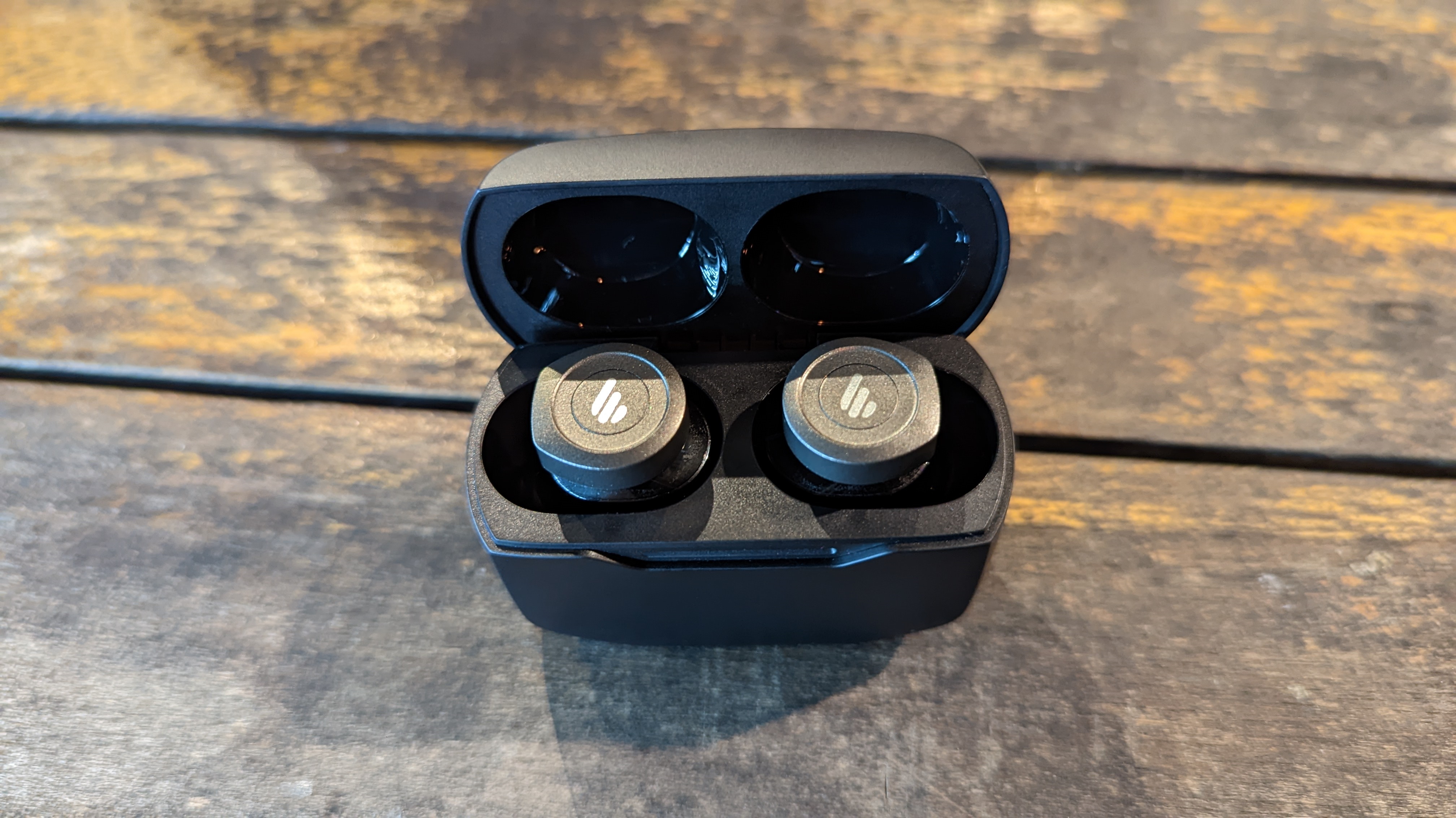 Edifier W240TN earbuds on a wooden table