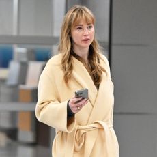 Jennifer Lawrence wearing a yellow coat, black pull-on pants, and Tory Burch Sport Mary Janes