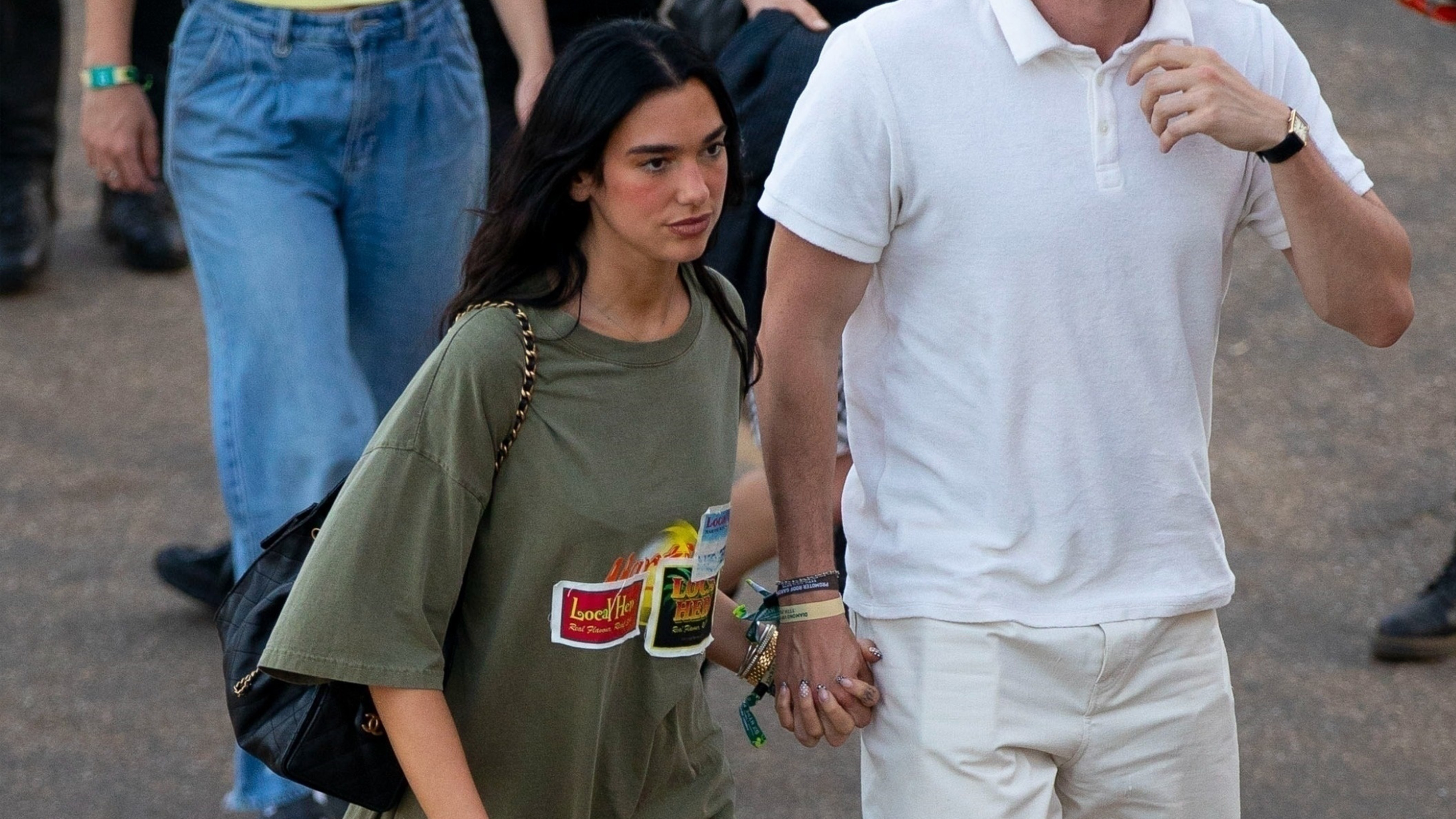 Dua lipa wears an oversize graphic t-shirt, denim shorts, a black chanel bag, and black moto boots.