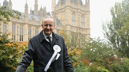 conservative mp laurence robertston outside westminster with rosette