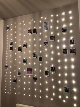 A grey painted ceiling and wall decorated with fairy lights and polaroids.