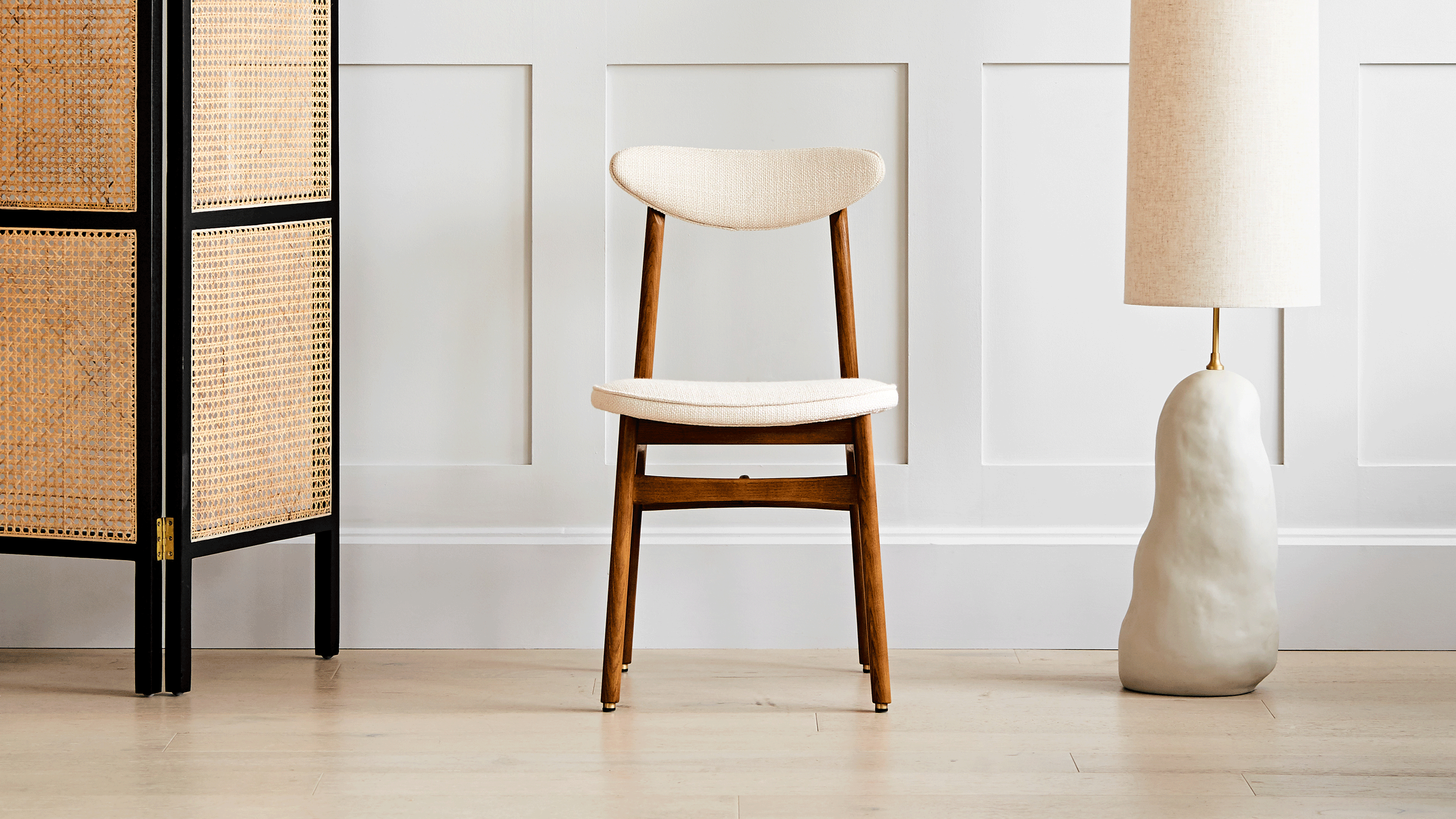 mid-century dining chair with lamp and rattan divider against wall panelling