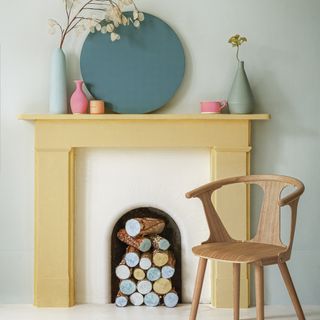 fireplace with white wall flower vase over it and wooden chair