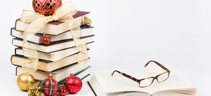 Gift of knowledge concept with a pile of books and reading glasses with Christmas ornaments