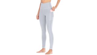 A model from the waist down wearing light gray high-waisted leggings with pockets, for the best leggings on Amazon.