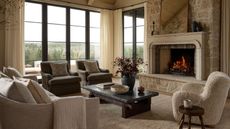 joon loloi fall collection neutral cozy living room with a large stone fireplace and a boucle armchair