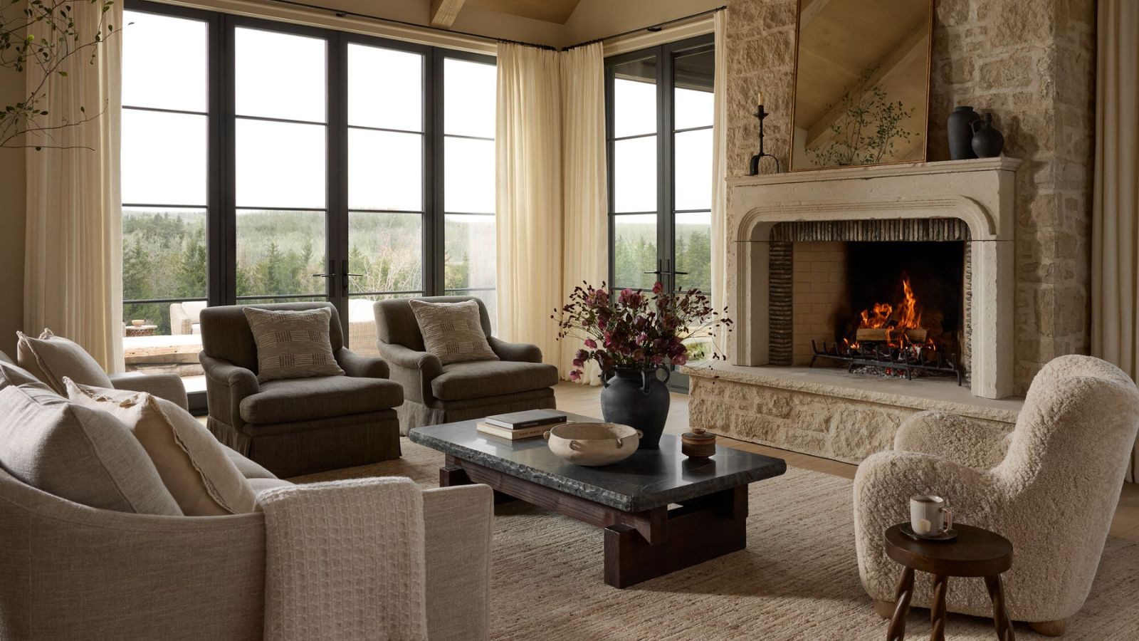 joon loloi fall collection neutral cozy living room with a large stone fireplace and a boucle armchair