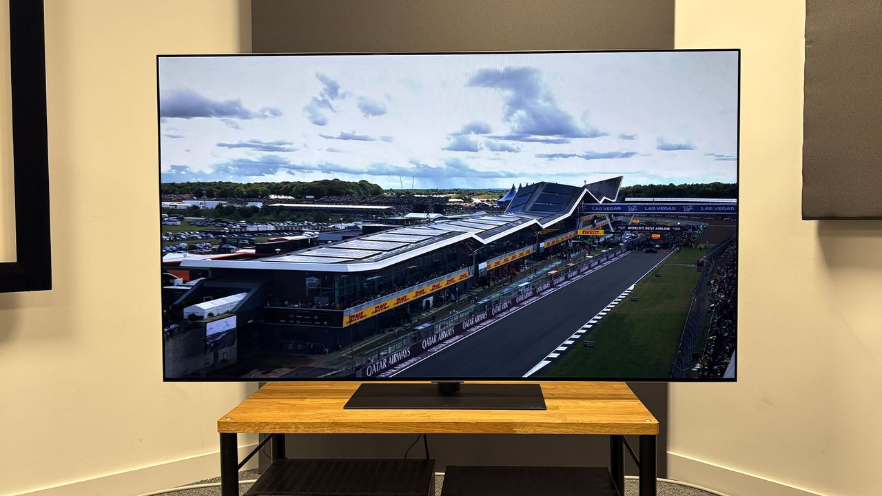 The 65-inch LG G5 OLED TV pictured on a wooden rack. On the screen is a still from Netflix F1 series Drive to Survive.