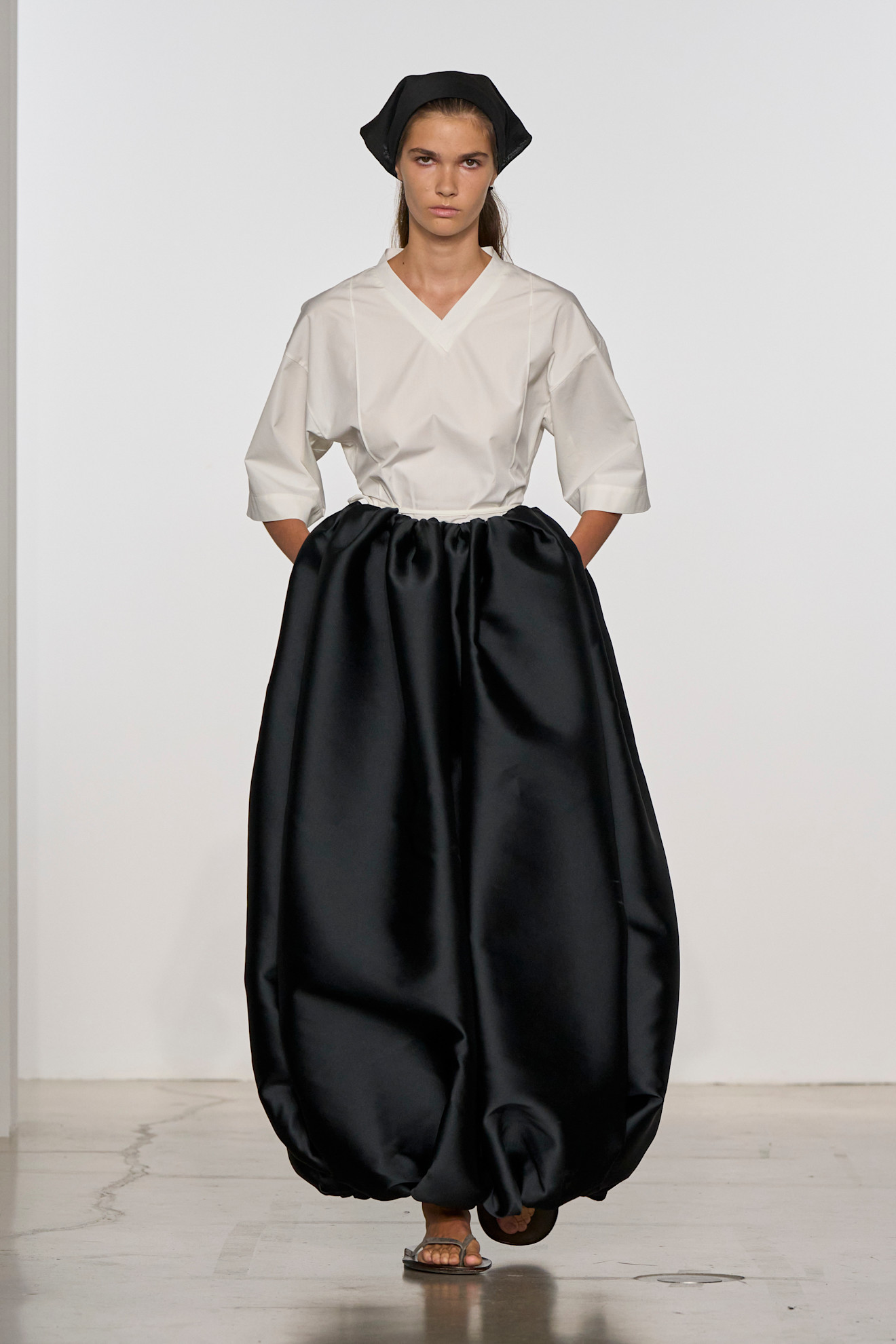 A model at the ss26 Calvin Klein show wearing a white V-neck top with billowy ballon pants.