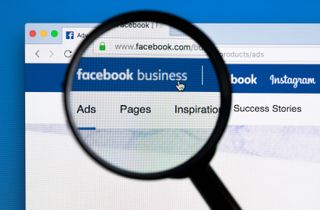A magnifying glass examining a Facebook page