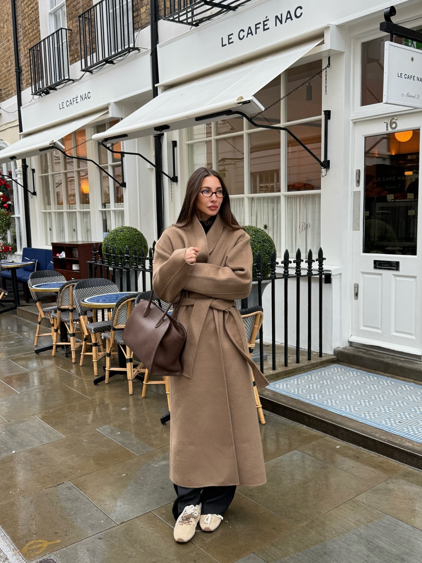 Influencer wears a belted brown long coat.