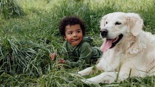 Boy laying in grass with retriever