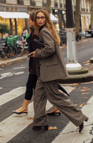 woman crossing the street in new york city wearing a brown blazer and brown pants and brown boots