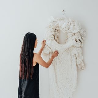 Woman touching artwork on wall, Garment by Ayumi Kajiwara