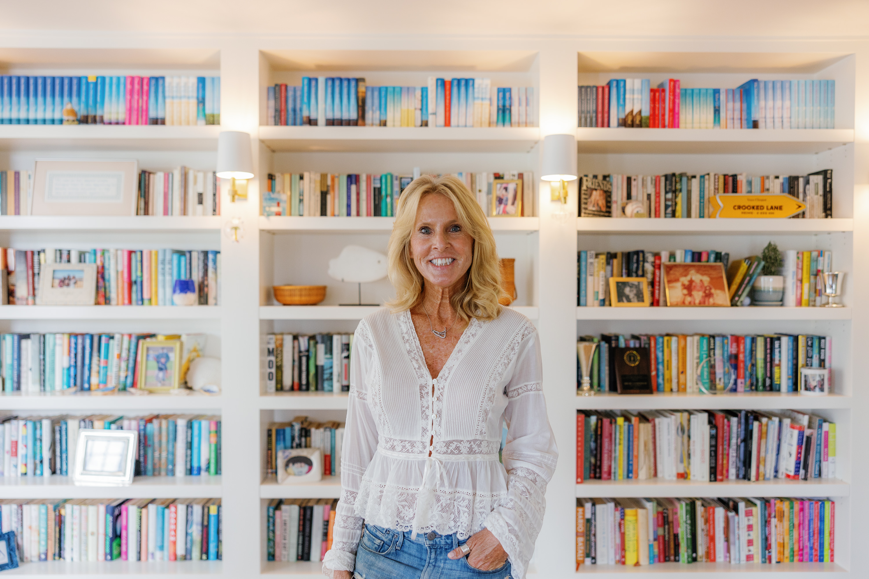 author elin hilderbrand poses in front of her book shelf