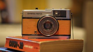 An Olympus Trip 35 resting on a pile of books